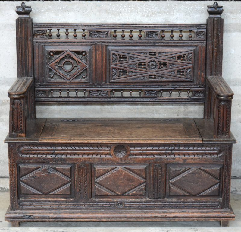 Een eikenhouten kofferbank met gebeeldhouwde panelen en assymetrisch opengewerkte rug. Vroeg XIXe eeuw.