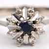 Een 14 K witgouden ring bezet met diamanten met een gezamenlijk gewicht van +- 0,16 ct. en een centrale saffier van +- 0,10 ct.