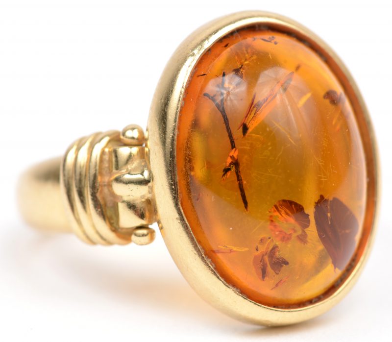 Een 18 K geelgouden ring met een gepolijste amber met zaadjes binnenin.