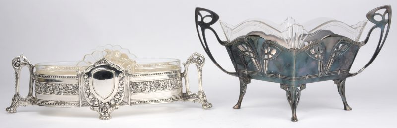 Twee milieu-de-tables met geslepen glazen coupes in verzilverd metalen montuur, waarbij één in barokke stijl en één in art-nouveaustijl.