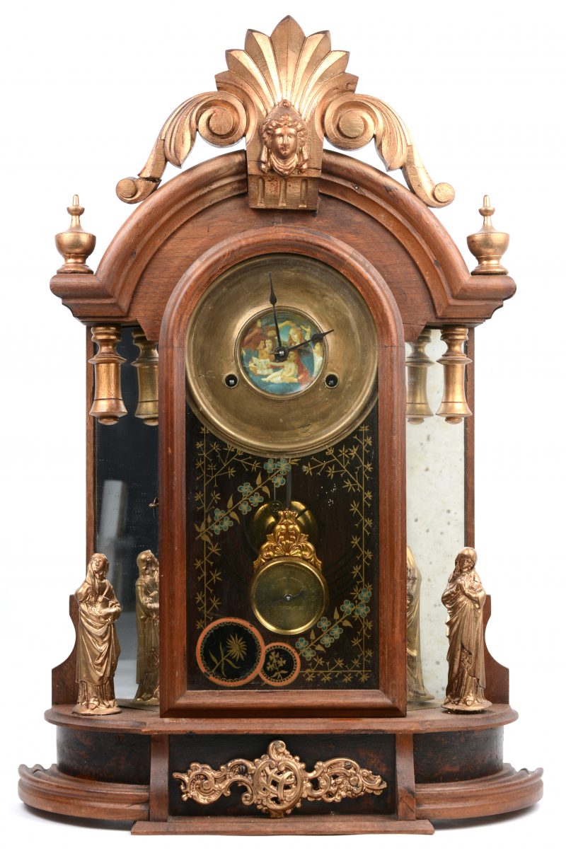 Een houten schouwklok met uurwerk achter glas en geflankeerd met spiegeltjes.