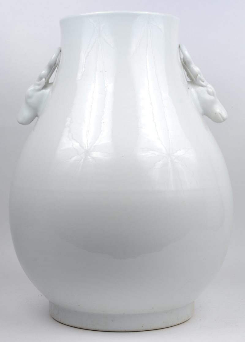 Een vaas van monochroom wit porselein met hertenkoppen als handvatten.