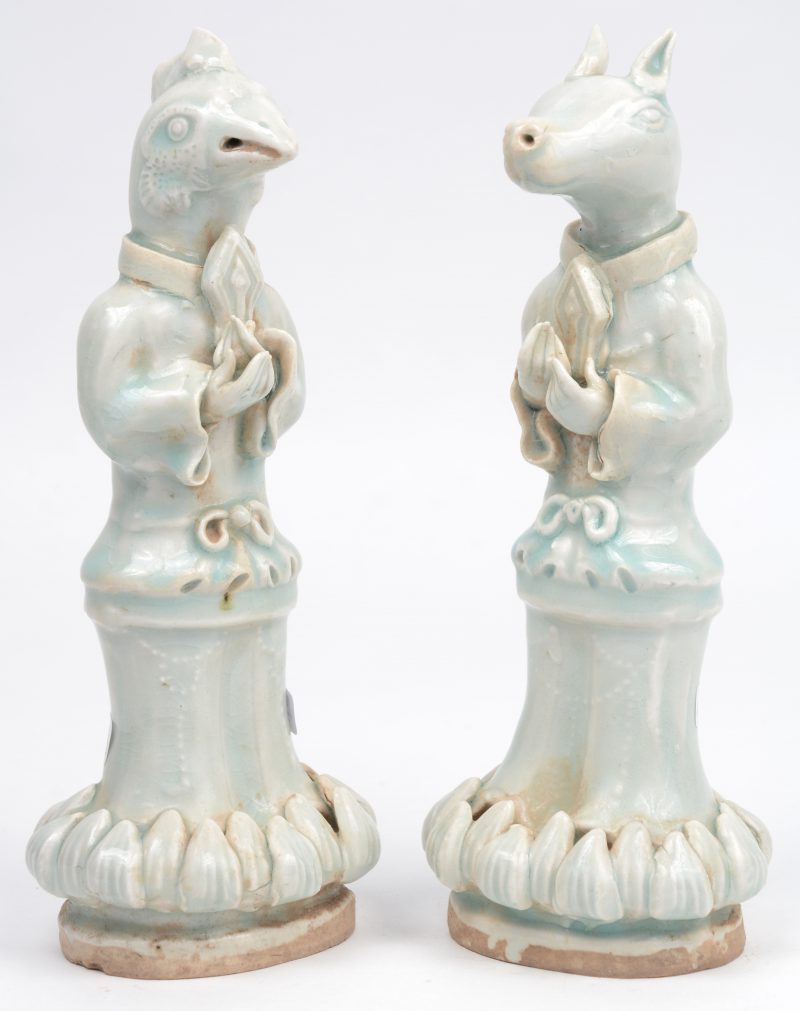 Een paar beeldjes van Chinees porselein in de vorm van figuren met dierenhoofden.