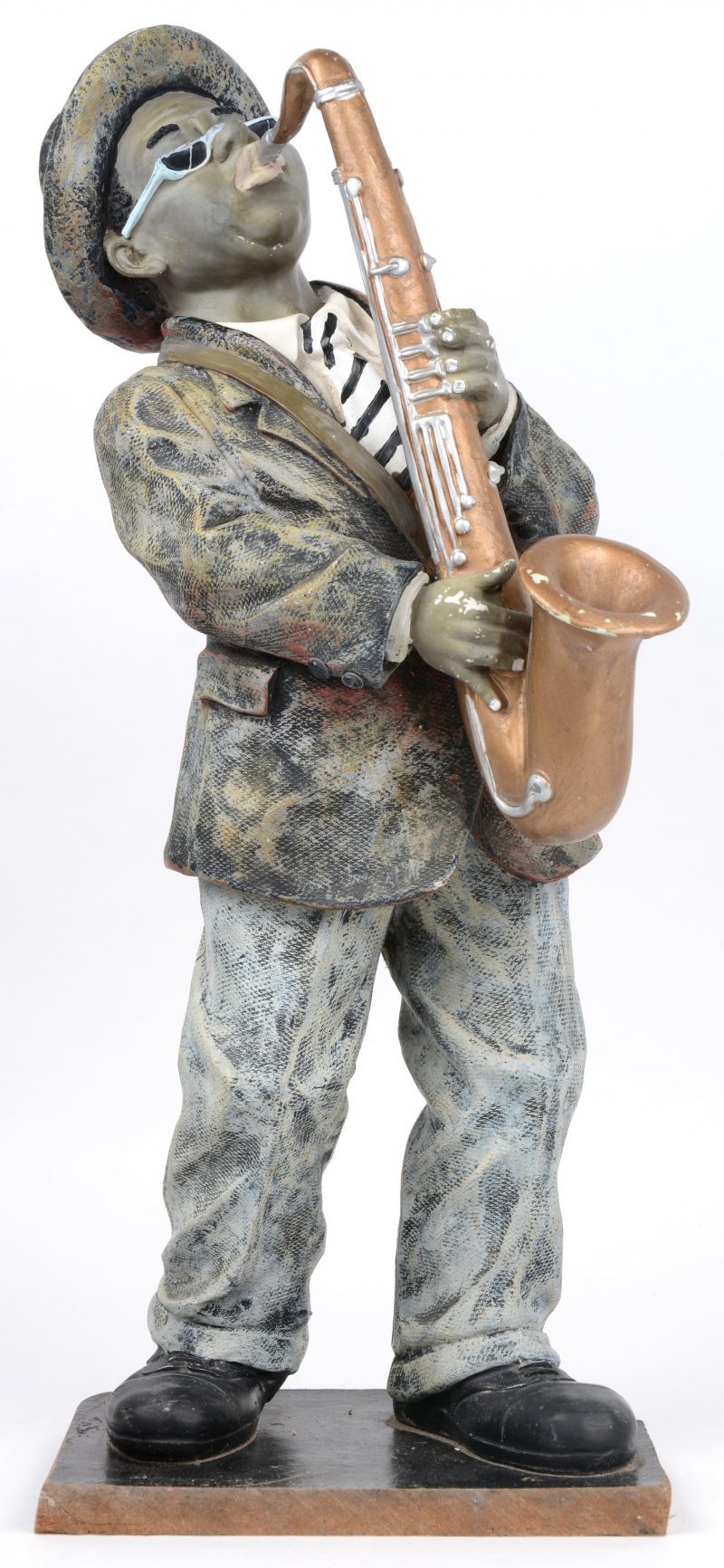 “Jazzsaxofonist”. Een beeld van meerkleurig kunststof op houten voetstuk.