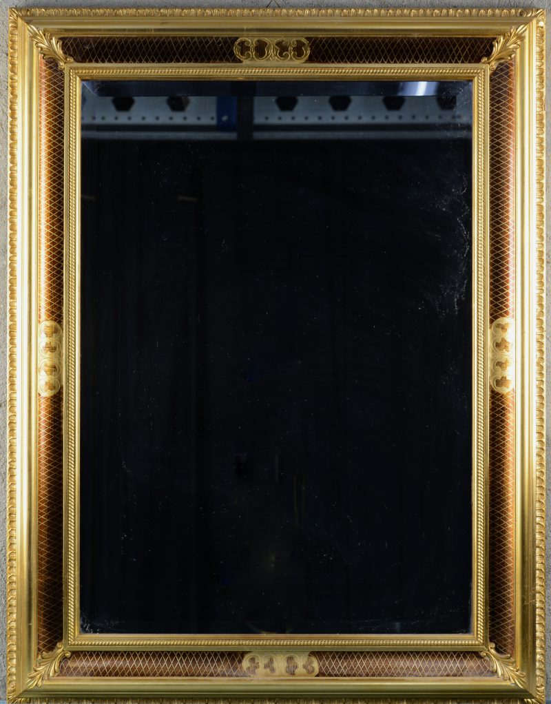 Een rechthoekige spiegel met deels vergulde houten rand en geslepen glasranden.