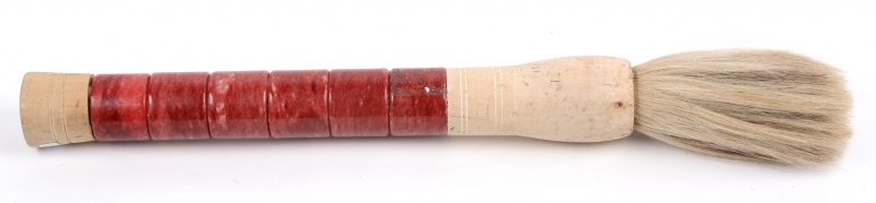 Een kaligrafisch penseel met handgreep van rood mineraal en hout.
