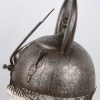 Een Perzische Kulah Khud helm met een gedamasceerd en geciseleerd decor op zwarte fond versierd. Boven op de bolle helm een vierhoekige punt en twee aigrettehouders en achteraan een maliënlap. XIXde eeuw.