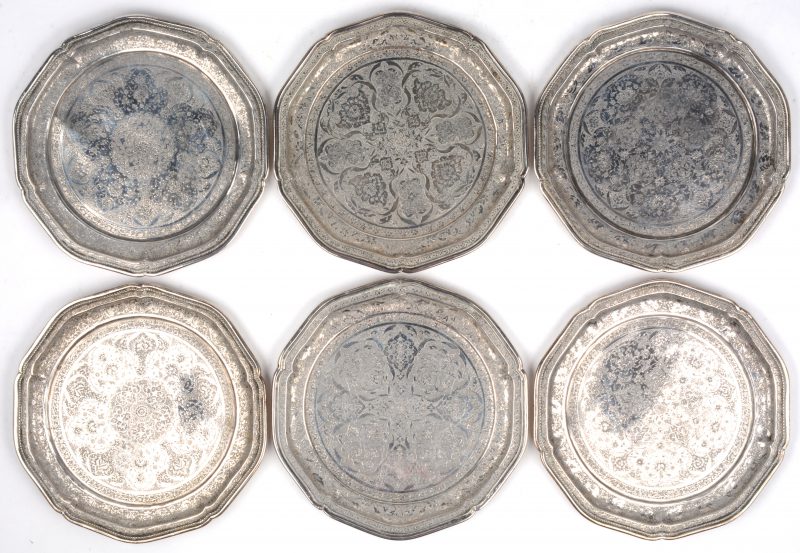 Zes kleine bordjes van gedreven en geciseleerd zilver versierd met een bloemenmotief rond een medaillon. Gechantourneerd rand met parelfries. Perzië, Qadjar, begin XXste eeuw. Onderaan gemerkt: 84% en Made in Iran.