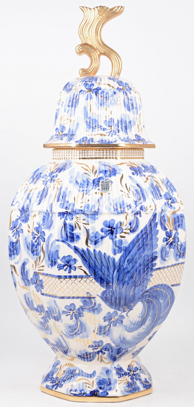 Een achthoekige dekselvaas van aardewerk met een blauw-wit en verguld bloemendecor. Schilfer aan het deksel.