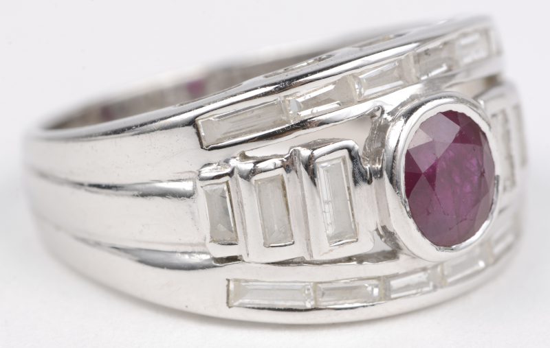 Een 18 K witgouden ring bezet met diamant baguetten met een gezamenlijk gewicht van +- 1,26 ct. en een ovale robijn van +- 0,75 ct.
