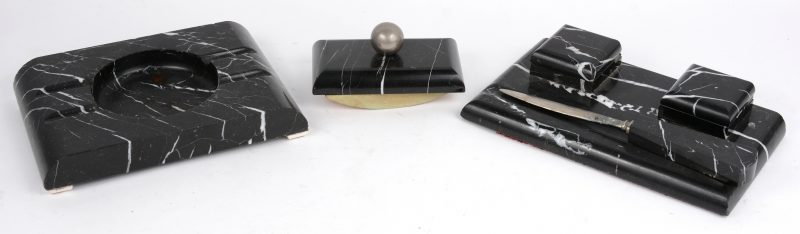 Een vierdelig bureaustel van zwart marmer, bestaande uit een inktstelletje, een brievenopener, een vloeiblok en een asbak.