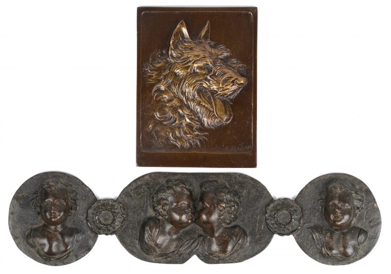 Twee bronzen reliëfs, waarbij één met engeltjes en één met een hond. De tweede gesigneerd.