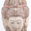Een gepolychromeerd stenen Boeddhahoofd met drie gezichten. Op houten sokkel.