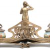 Een bronzen inktstel, versierd met een voruw met handspiegel. Met twee aardewerken intpotjes met bronzen dekseltjes. Naar art nouveau voorbeeld. Onderaan gemerkt.