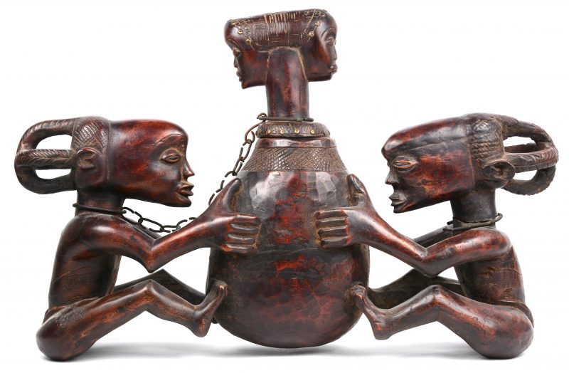 Medicijnpot van gebeeldhouwd hout, gesteund door twee personages. Deksel in de vorm van een janushoofd. Luba, DRC.