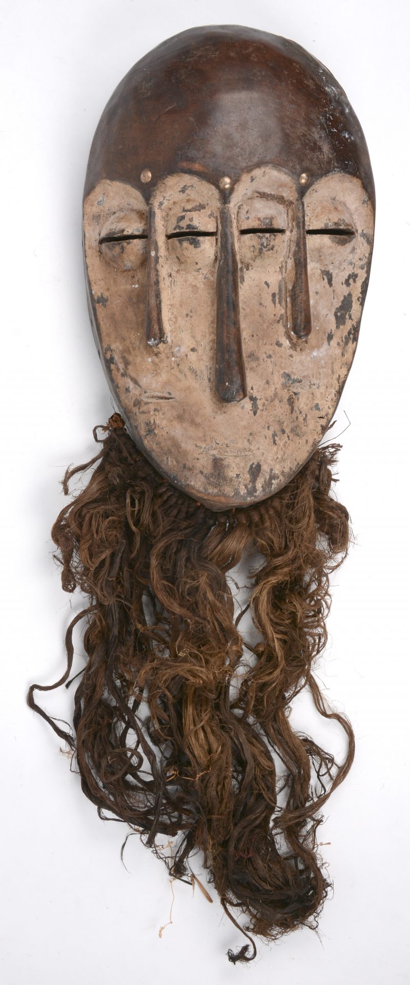 Een deels witgekleurd Afrikaans masker met vier ogen en drie neuzen. Vegetale baard.