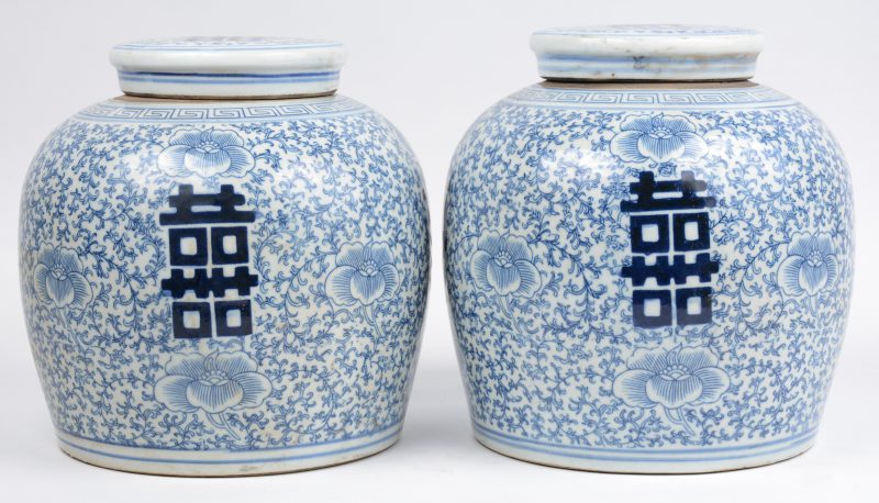 Een paar gemberpotten van Chinees porselein met een blauw op wit decor van tekens op een achtergrond van vegetale motieven.
