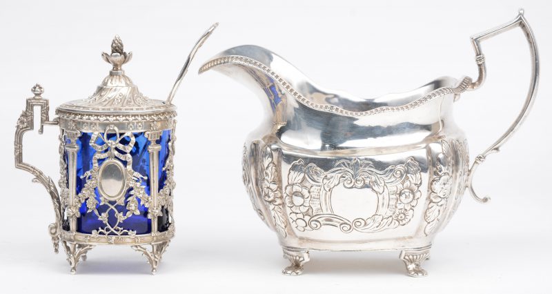 Twee stuks gedreven zilver, bestaande uit een Louis XVI mosterdpotje met lepeltje en blauw glazen recipiënt en een XIXe eeuws roompotje.