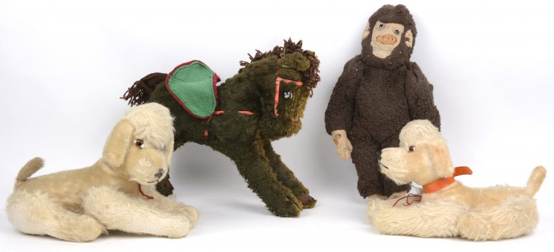 Een lot van vier oude pluchen diertjes, bestaande uit twee hondjes, een paard en een aap.