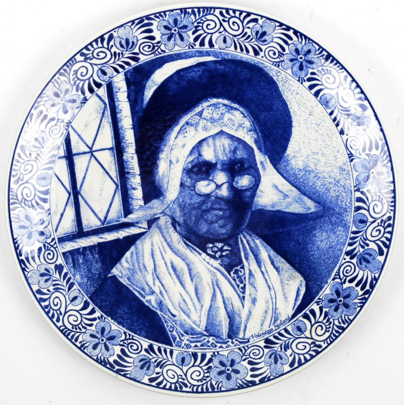 Een aardewerken bord met blauw op wit decor. Onderaan gemerkt.