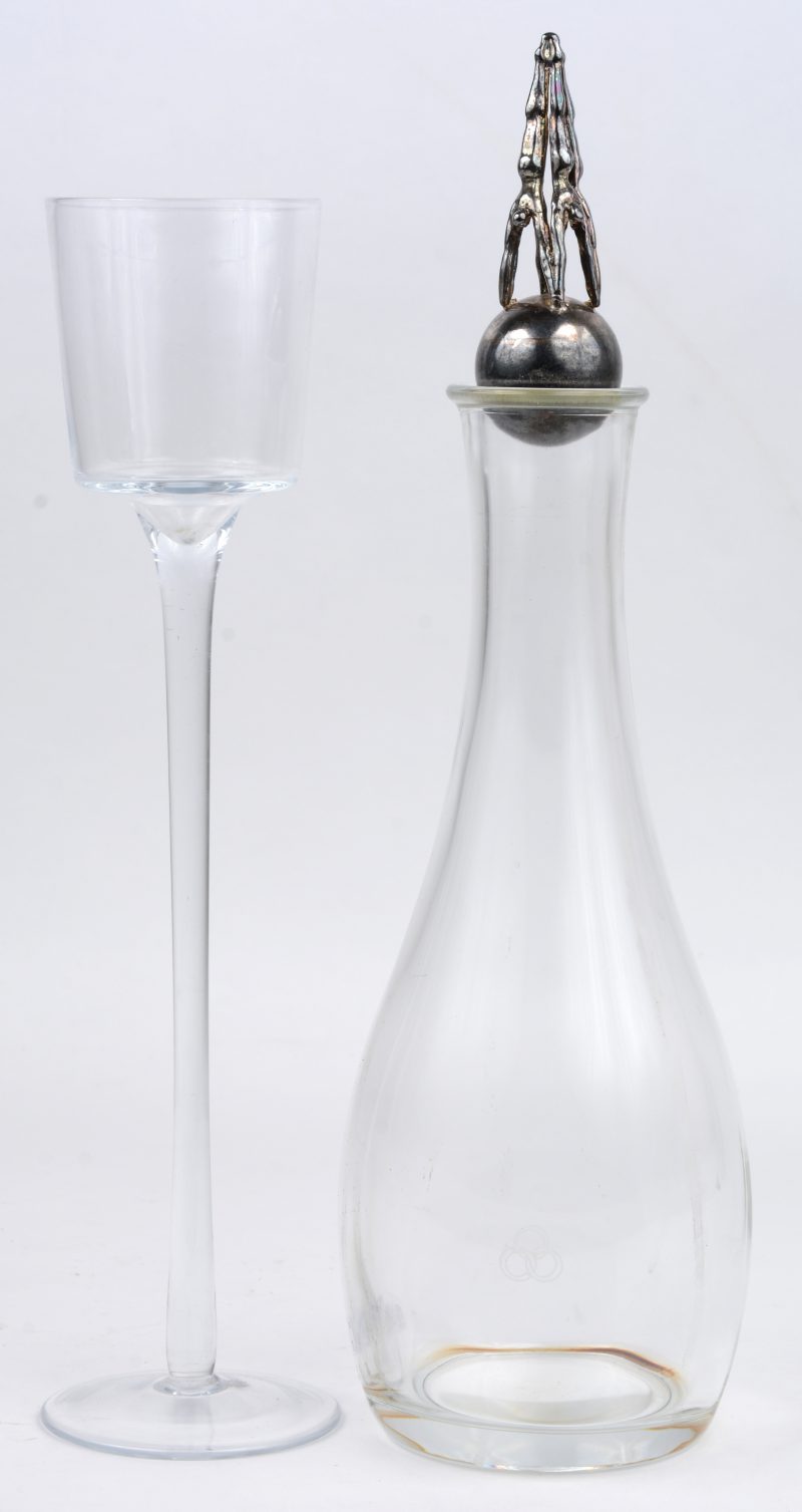 Een kleurloos glazen karaf met moderne metalen stop. Bijgevoegd een hoog glazen designglas.