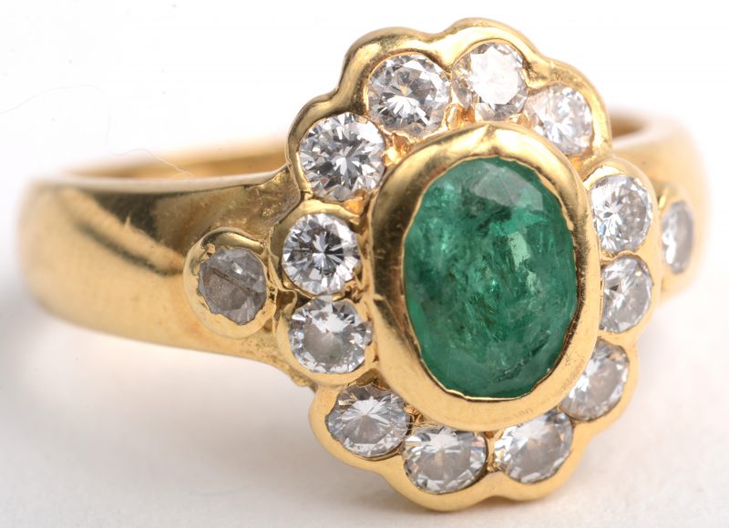 Een 18 K geelgouden ring bezet met briljanten met een gezamenlijk gewicht van +- 0,70 ct. en een centrale smaragd van +- 0,75 ct.
