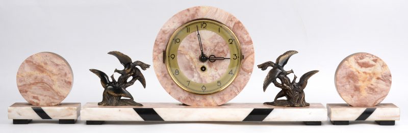 Een driedelig art deco klokstelletje van rose en beige marmer en het uurwerk geflankeerd door bronzen vogeltjes.