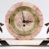 Een driedelig art deco klokstelletje van rose en beige marmer en het uurwerk geflankeerd door bronzen vogeltjes.