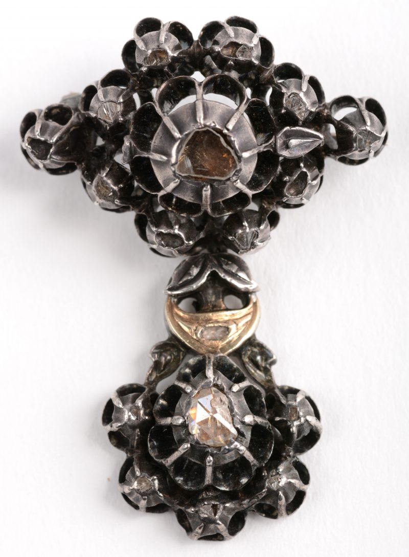 Een zilveren broche in de vorm van een Vlaams Kruis bezet met diamanten oude slijp met een gezamenlijk gewicht van 0,60 ct.