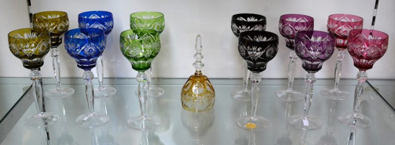 Een reeks van twaalf geslepen kristallen glazen met gekleurde kelken.