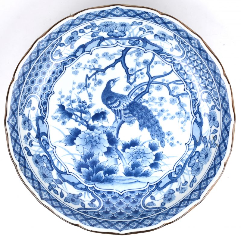 Een recente schaal van Chinees porselein met een blauw op wit decor van een pauw in een bloeiende struik. Onderaan gemerkt.