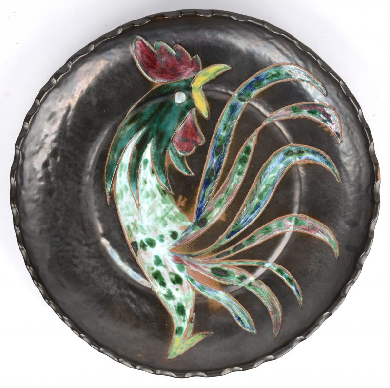 Een sierschotel van aardewerk met een meerkleurig decor van een haan. Onderaan gemerkt ‘Wilfred’.