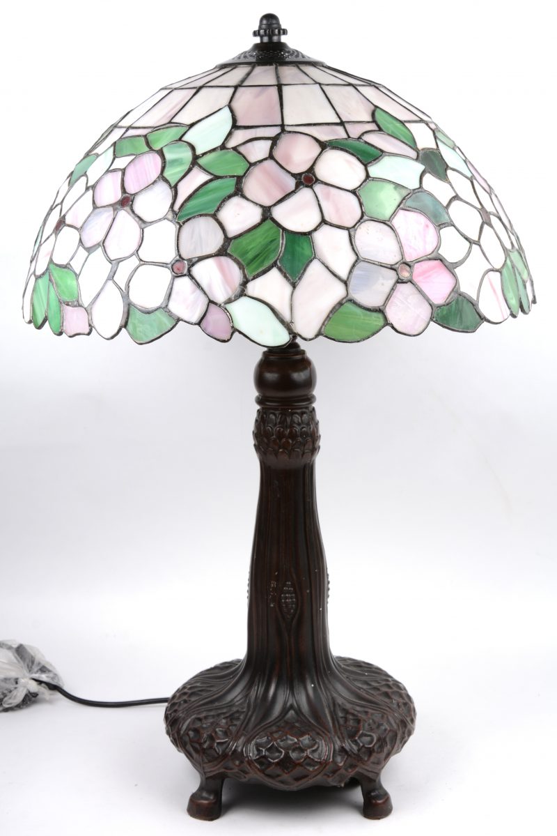 Een lampvoet met een kap van glas in lood in de stijl van Tiffany.