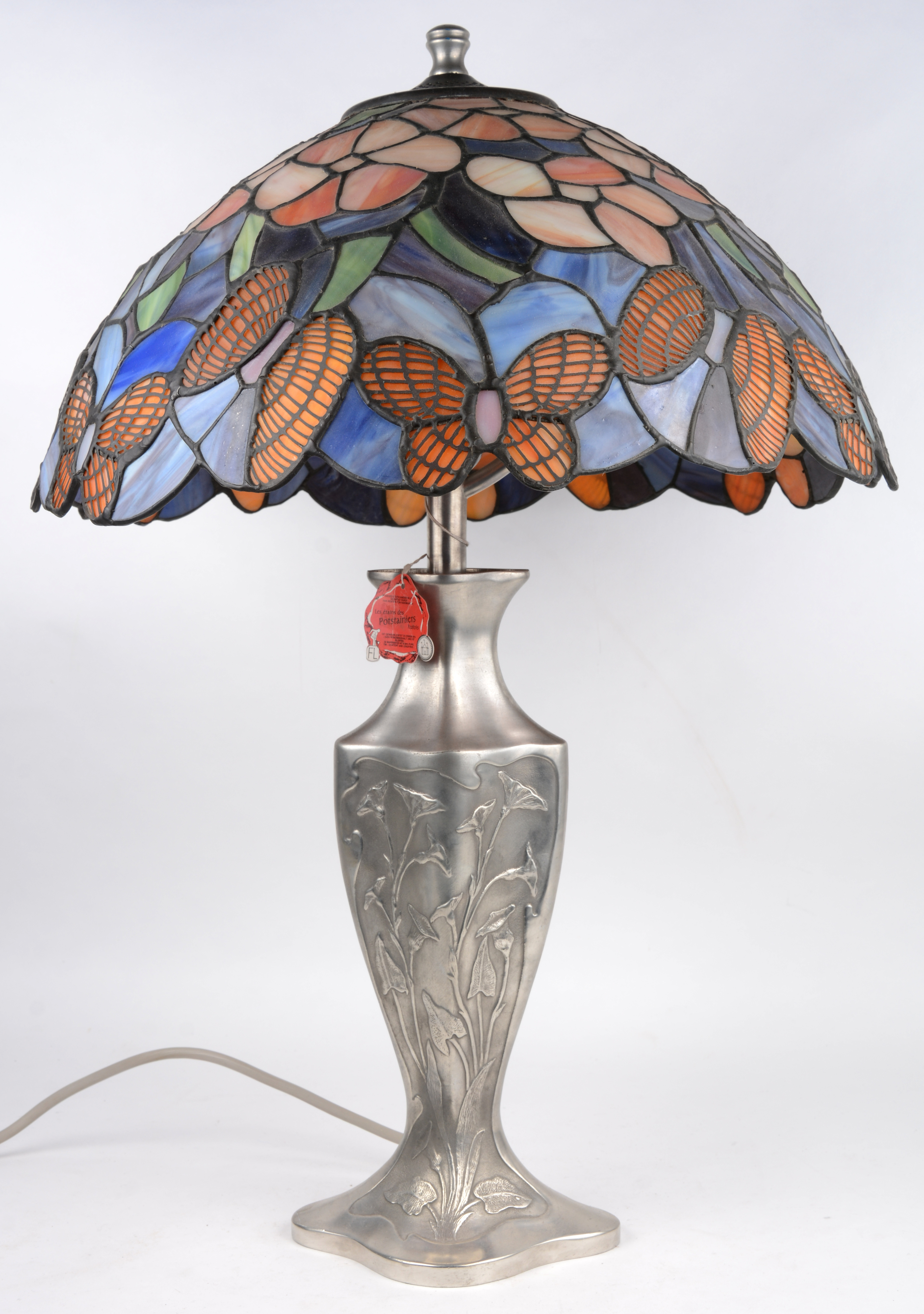 Een schemerlamp met tinnen lampenvoet en een kap van glas in met vlinders en bloemen. – Jordaens N.V. Veilinghuis