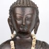 Een zittende Boeddha van brons. Met kralensnoer van gesculpteerde ivoren schedeltjes. Op losse houten sokkel.