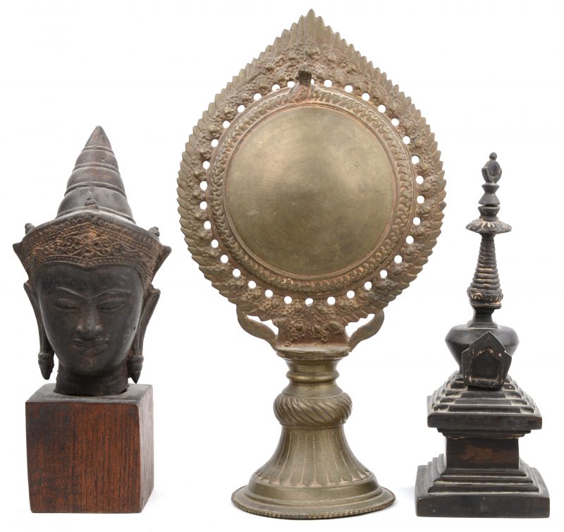 Drie stuks brons, waaronder een Boeddhahoofd op houten sokkel.