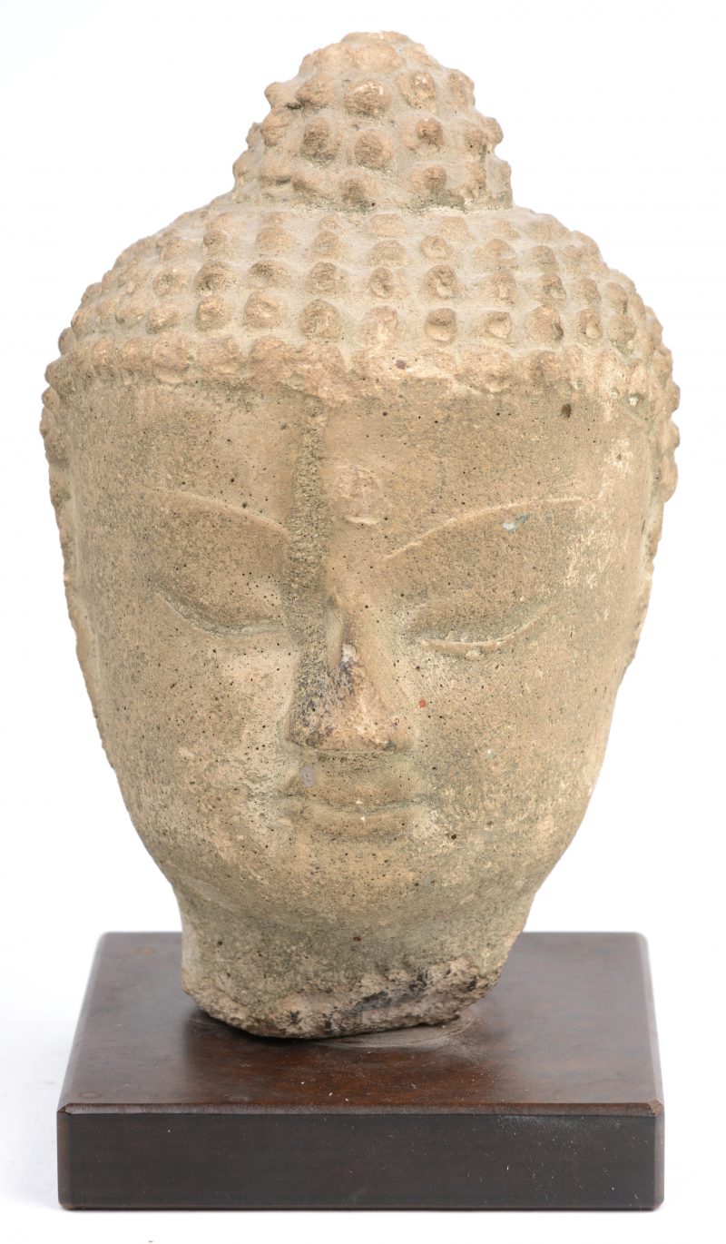 Een antiek stenen Boeddhahoofdje op voetstukje van masoniet.