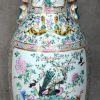 Een vaas van Chinees porselein met een meerkleurig decor van diverse vogels in bloeiende struiken en met handvatten in de vorm van Fo-honden.