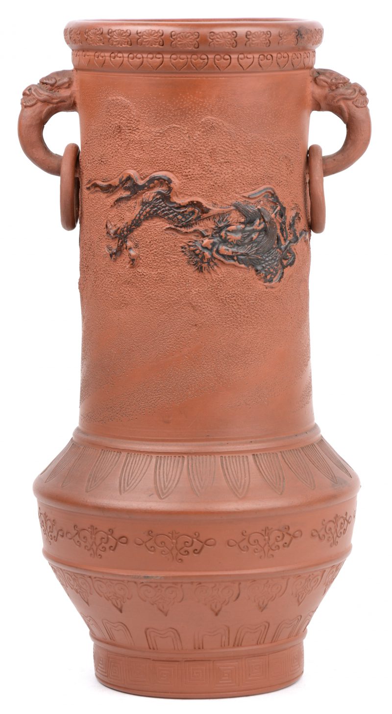 Een Japanse terracotta vaas met ringen aan de handvatten en met een draak in het decor. Onderaan met stempel ‘Raku’.