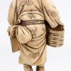 “Man met kikker in mand”. Een fijngesculpteerde ivoren okimono. Onderaan gesigneerd. Eerste helft XXe eeuw.