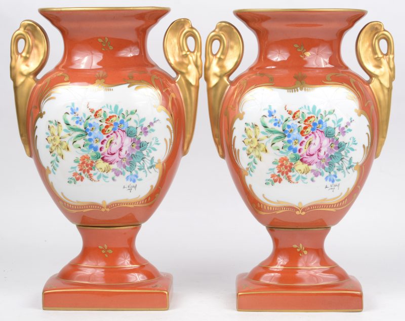 Een paar siervazen van meerkleurig en verguld porselein, versierd met handgeschilderde bloemendecors.