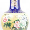 Een grote bolle vaas van Chinees porselein met een decor van pioenen en vogels en met vergulde teksten op kobaltblauwe fond.