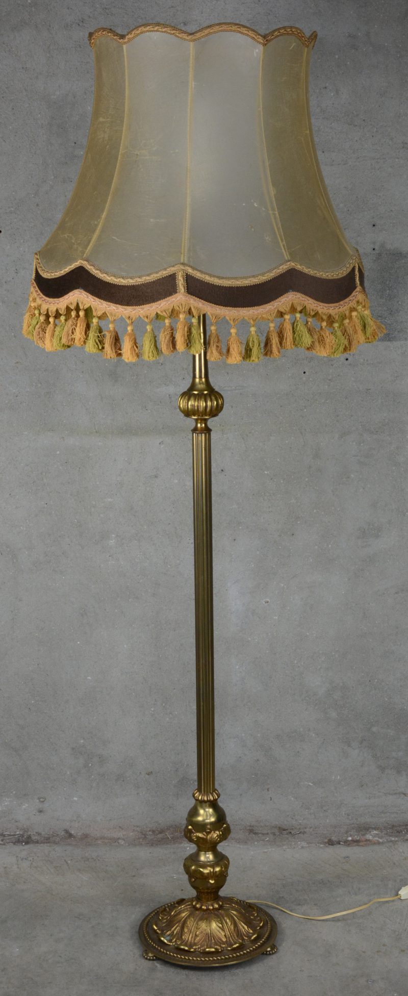 Een messingen staande lamp, de voet versierd met acantusbladeren.