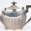 Een driedelige zilveren theeset met geribd decor en de theepot met houten handvat en dekselknop. Schotse keuren.