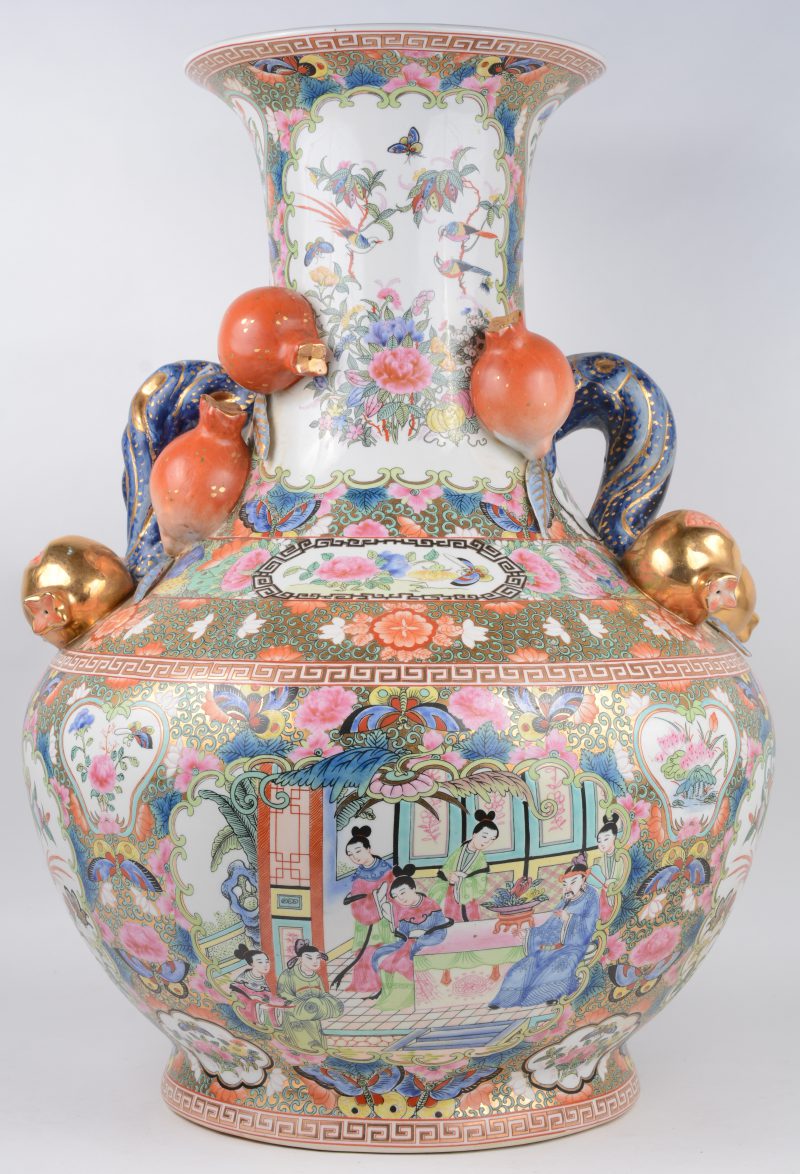 Een grote vaas van meerkleurig en verguld Chinees porselein met een Cantondecor van personages en met granaatappels in hoogreliëf. Onderaan gemerkt.
