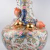 Een grote vaas van meerkleurig en verguld Chinees porselein met een Cantondecor van personages en met granaatappels in hoogreliëf. Onderaan gemerkt.