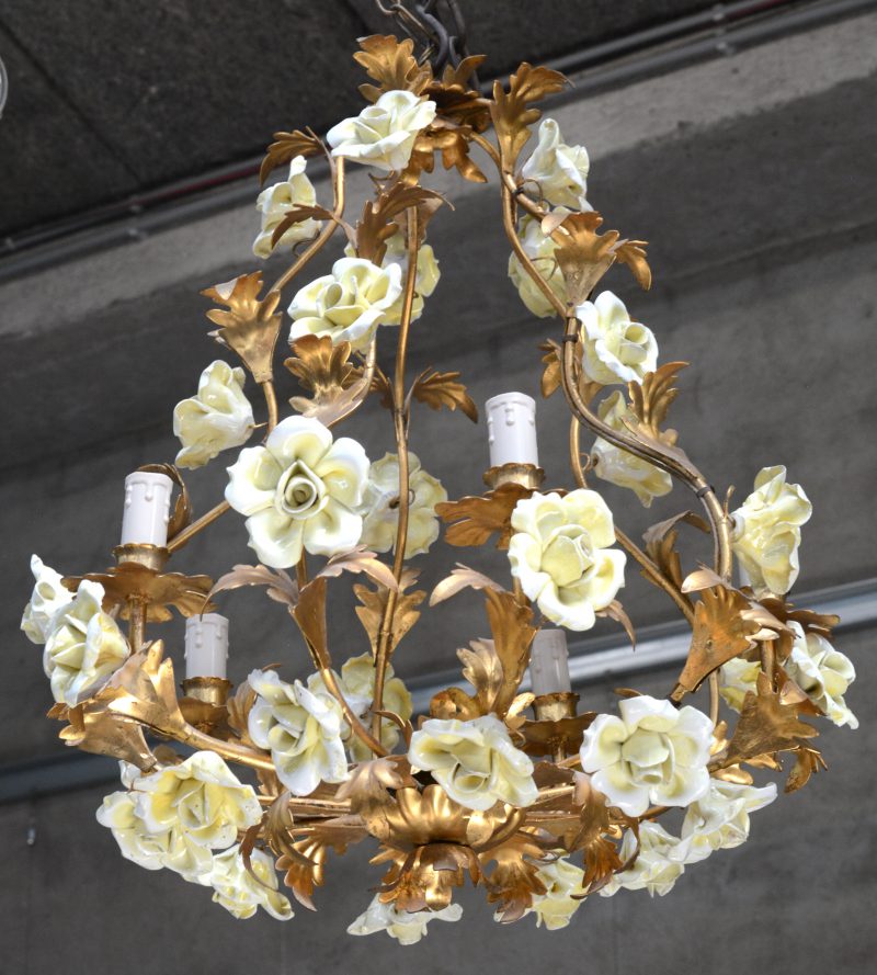 Een verguld smeedijzeren luchter, versierd met porseleinen bloemen.