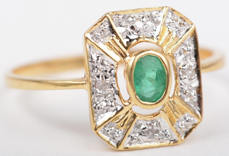 Een 18 K wit en geelgouden ring bezet met een smaragd van +- 0,20 ct en vier kleine briljantjes.