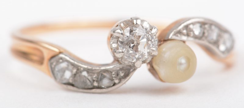 Een 18 K wit en geelgouden ring bezet met diamanten met een gezamenlijk gewicht van +- 0,20 ct. en een parel.