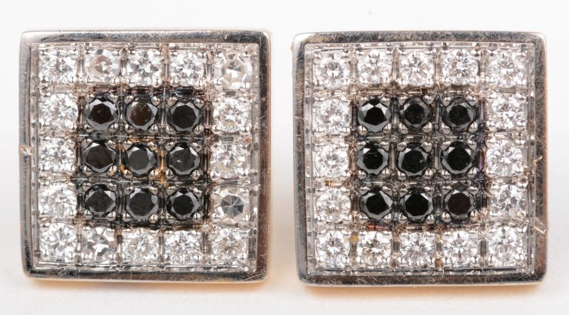 Een paar 18 K wit en geelgouden oorbellen bezet met briljanten en zwarte diamanten met een gezamenlijk gewicht van +- 0,50 ct.